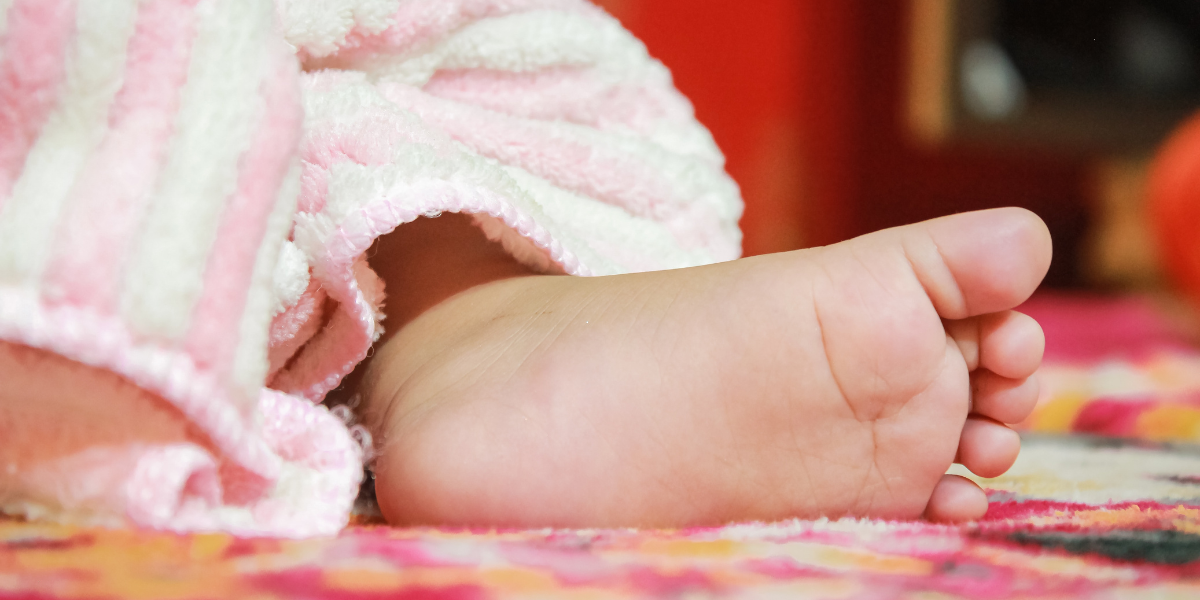 Adorable and cute baby foot showing baby toes with legs wrapped in warm blanket