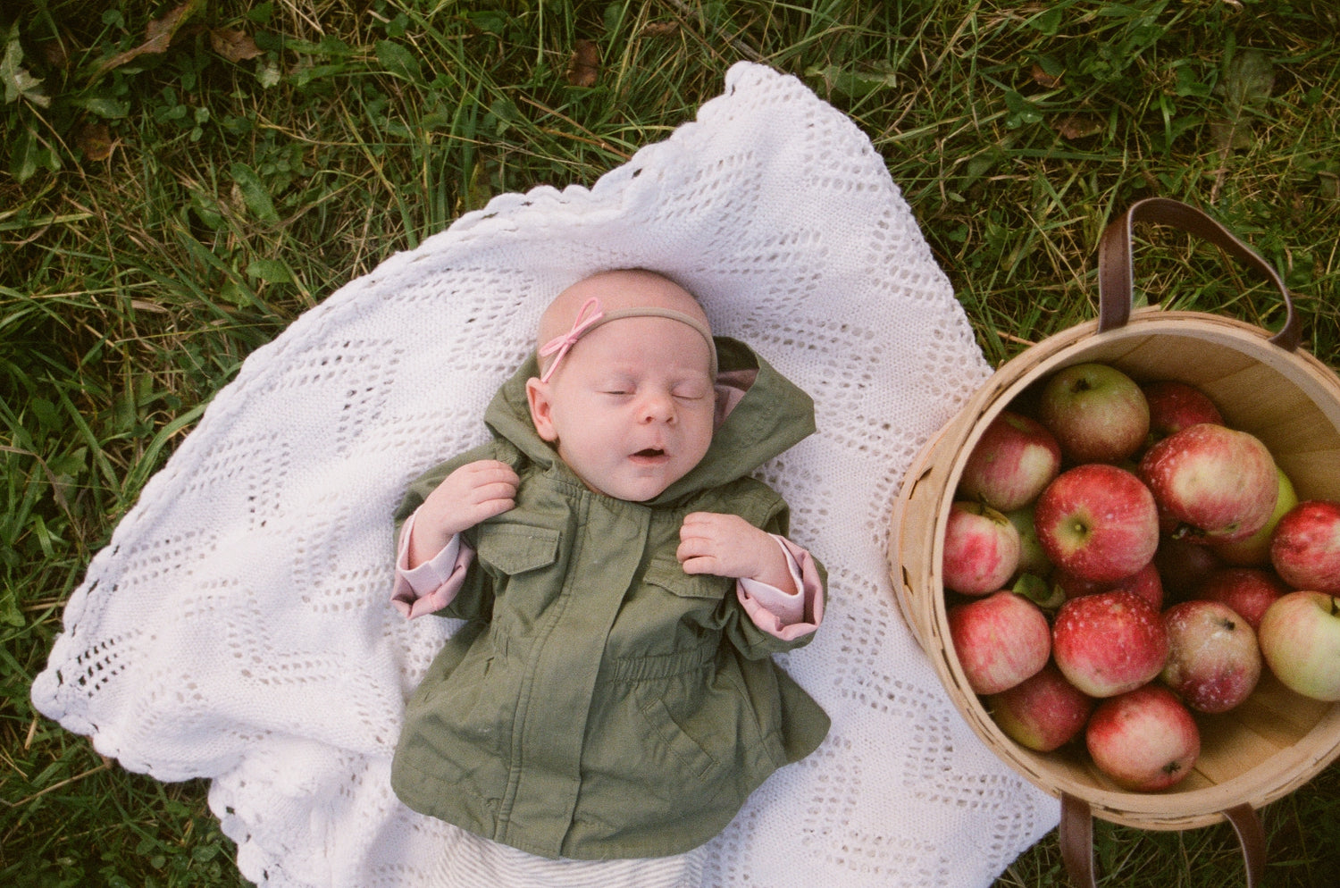 a-baby-lays-sleeping-next-to-a-basket-of-apples